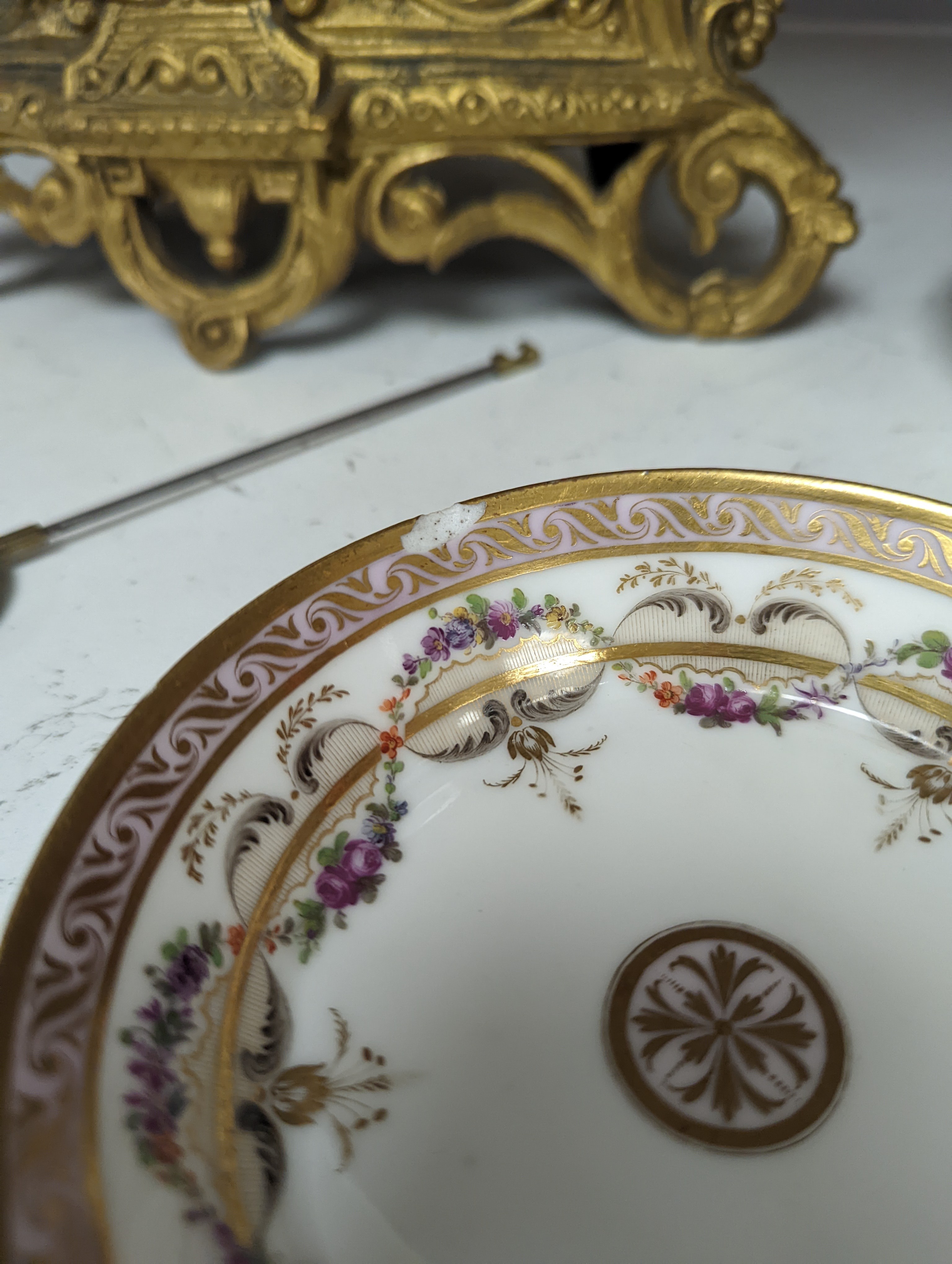 A Duc d'Angouleme coffee can and saucer painted with a puce chain of leaves on a salmon coloured ground and another painted with a flower chain, black feather and a gilt line, latter with stencilled red mark 'Manuf de M